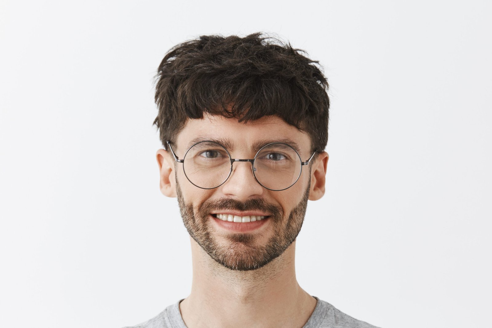 waist up shot of pleased and creative satisfied male entrepreneur in transparent glasses holding hands crossed on chest in self assured pose smiling joyfully answering on questions of students